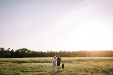 A family happily walking through a green field, envisioning their future project.