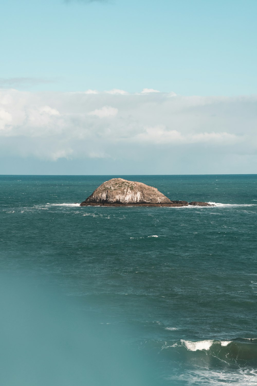 brown rock formation on blue sea under blue sky during daytime