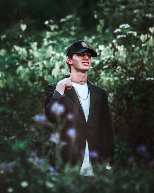 man in black suit jacket and black hat standing near green plants during daytime in Ontario Canada