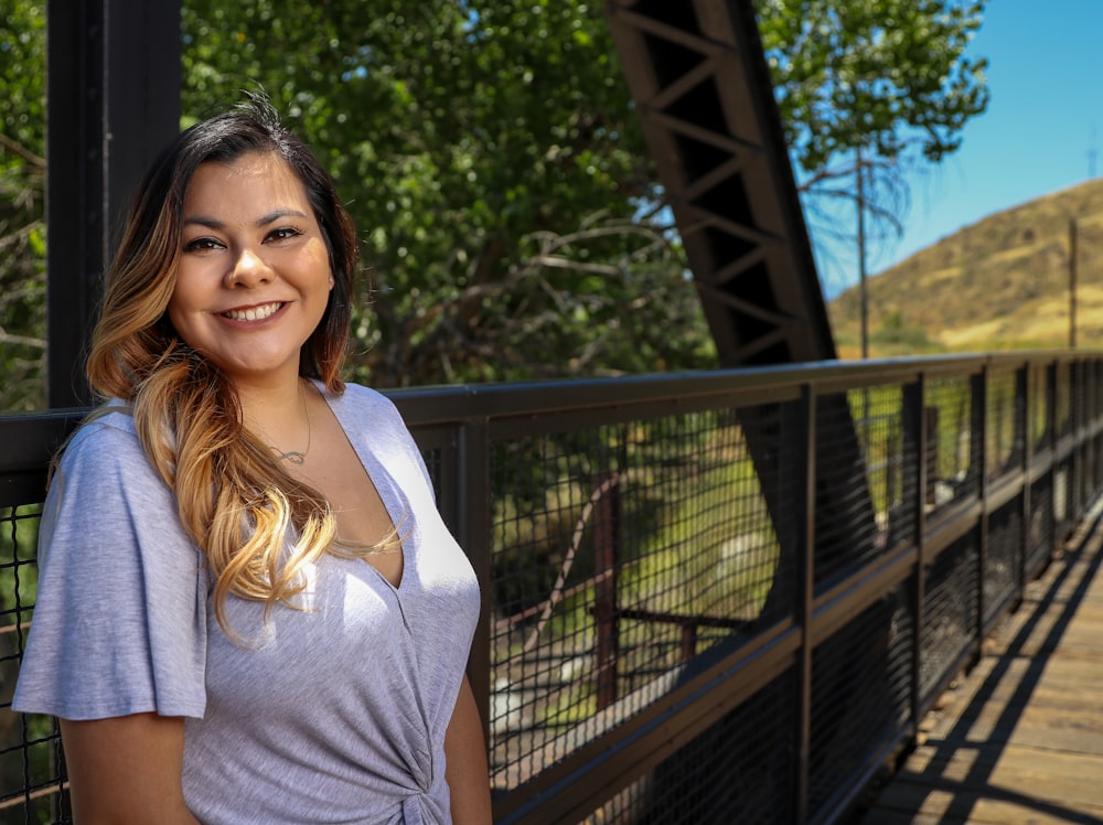 woman in white shirt standing near black metal fence during daytime