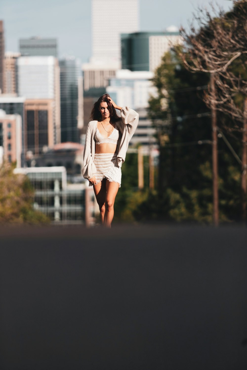 woman in white long sleeve shirt and white skirt standing on road during daytime