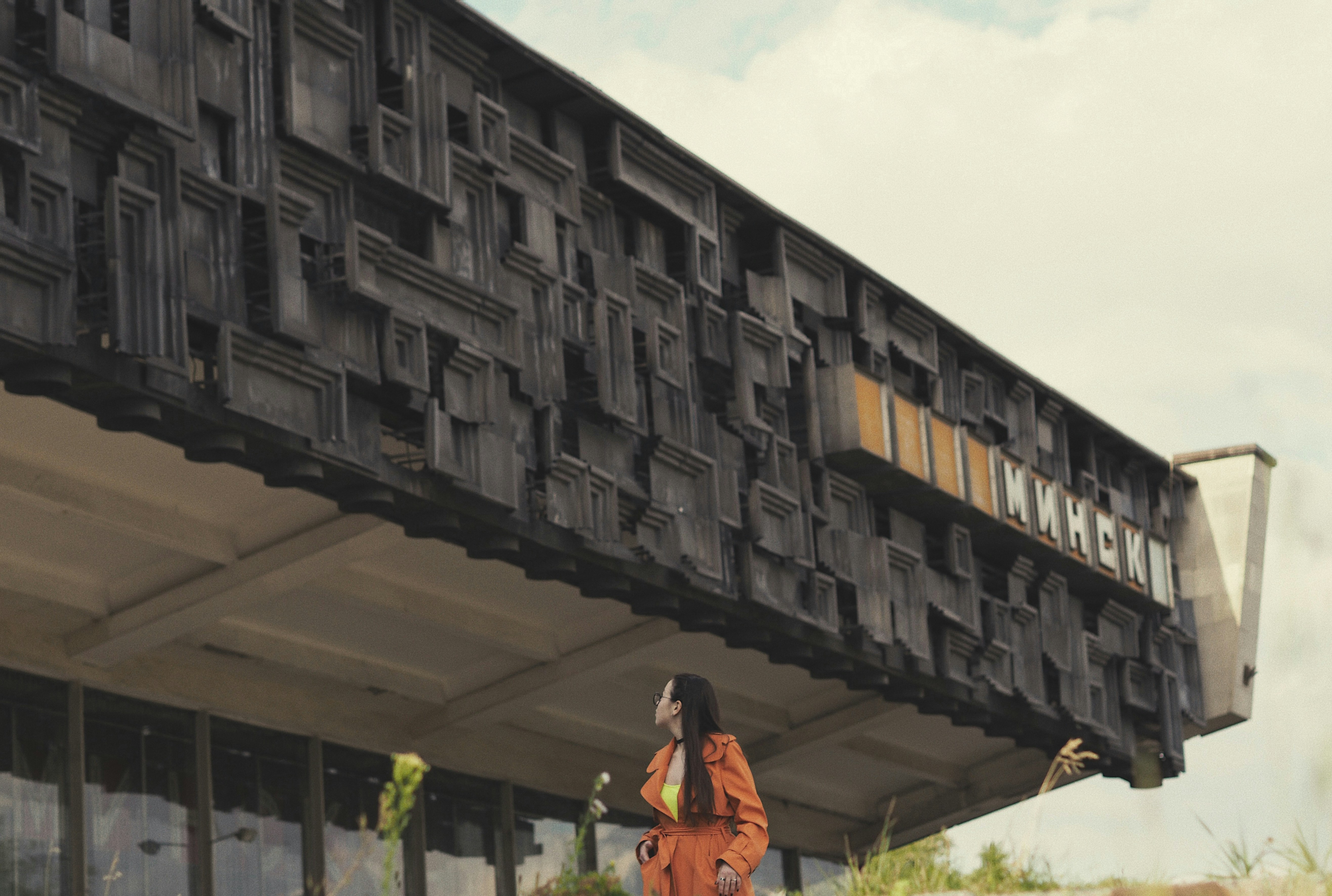 Hombre con camisa naranja de pie cerca de un edificio durante el día