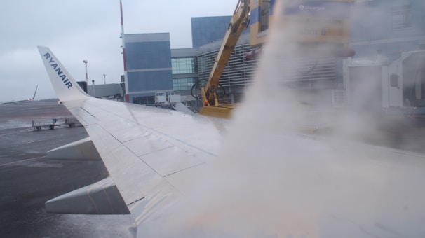Nighttime shot of a rmath de-icing vehicle spraying an aircraft wing under bright floodlights.
