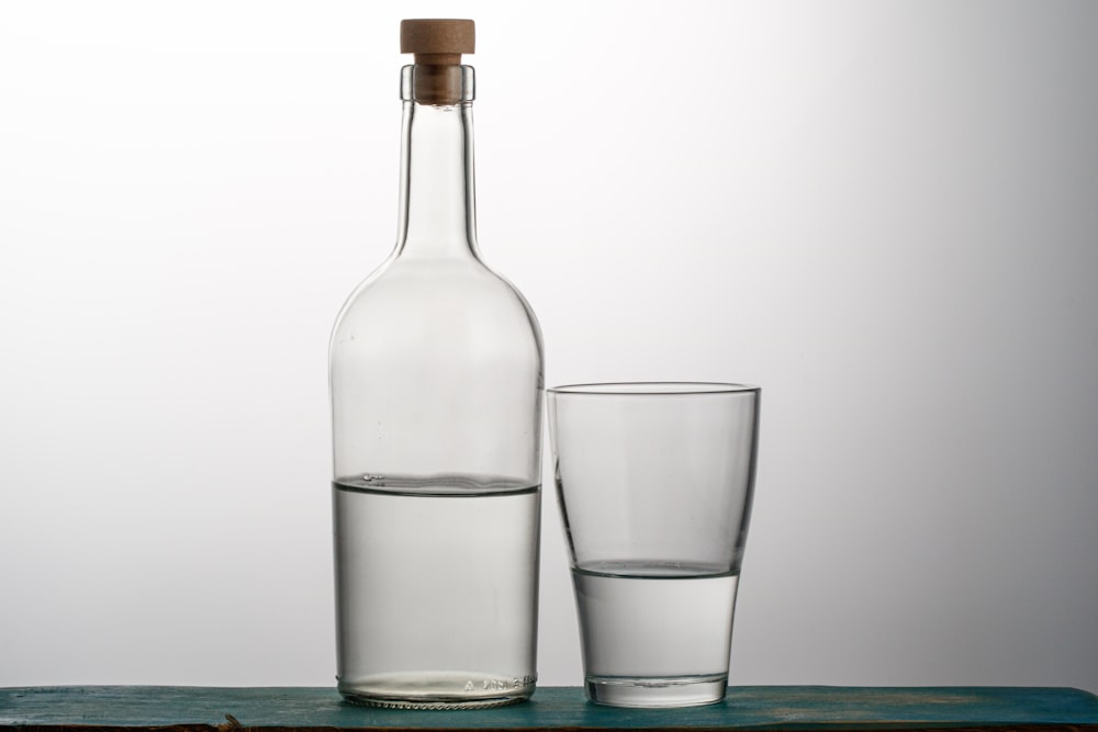 two clear drinking glasses beside bottle