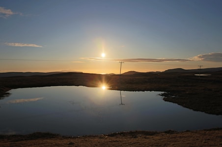 body of water near brown grass field during daytime