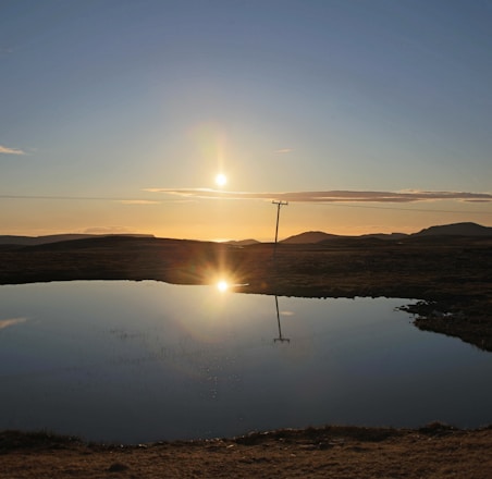 body of water near brown grass field during daytime