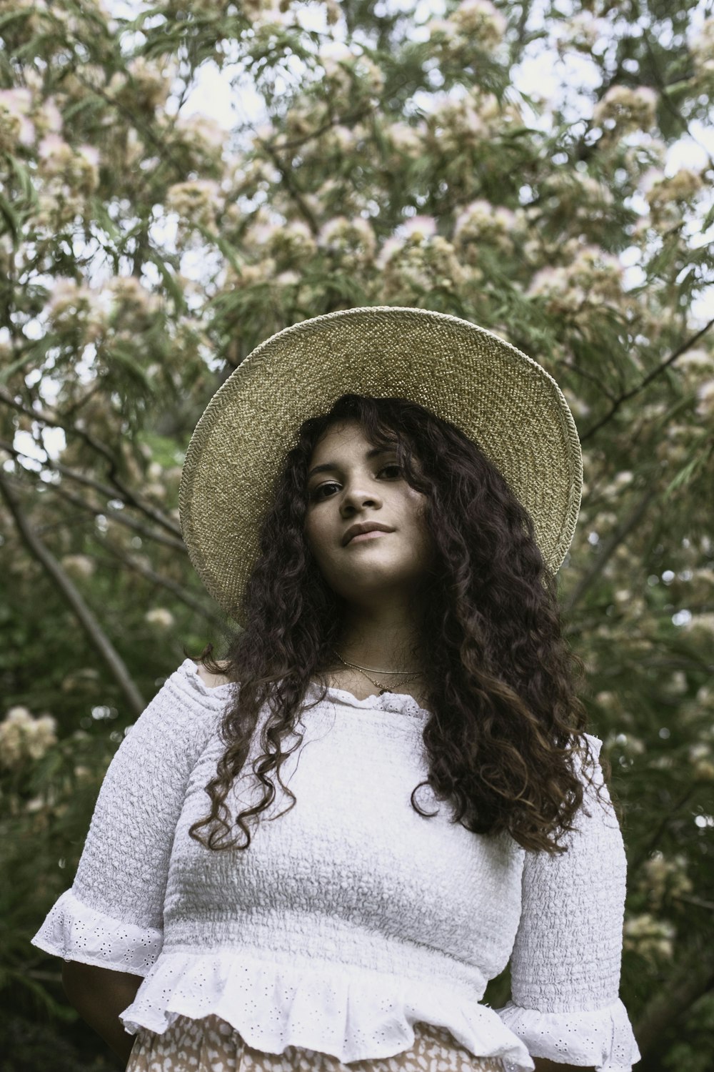 woman in white shirt wearing brown straw hat