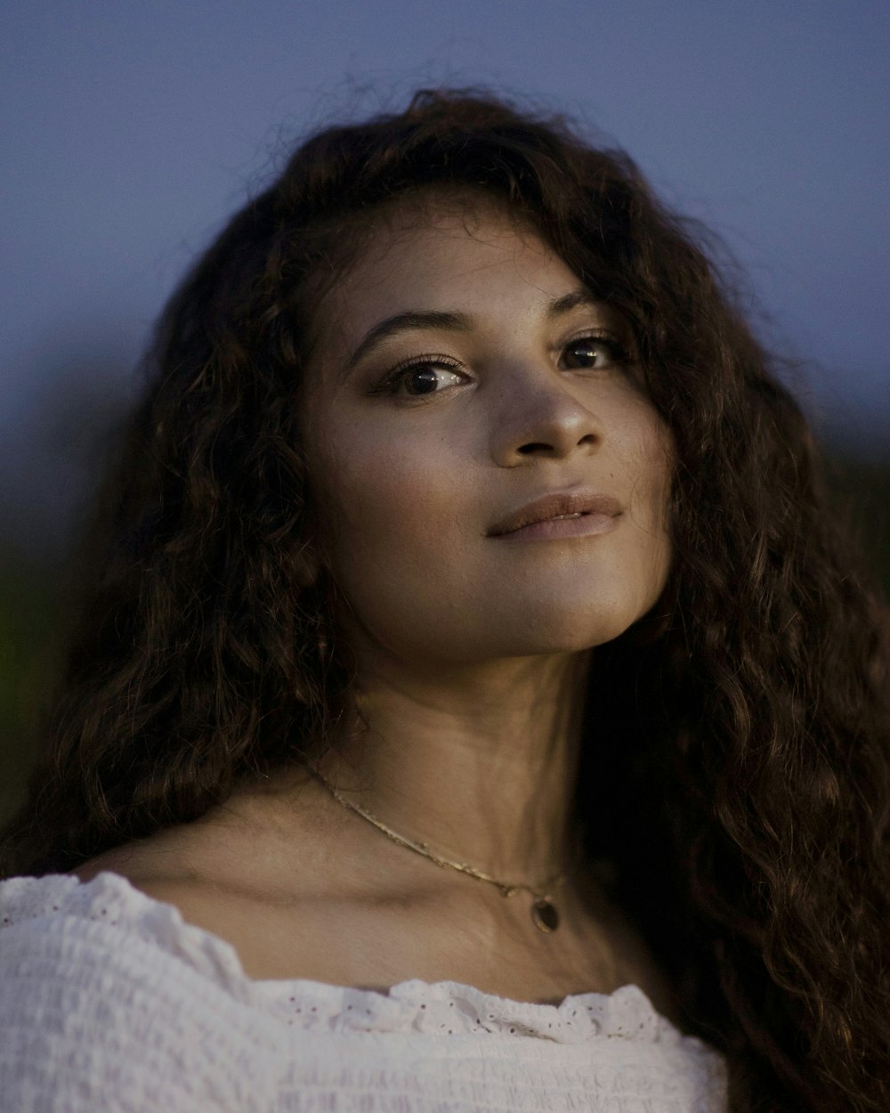 woman in white shirt wearing gold necklace