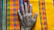 Close-up of a hand holding a vibrant huipil with intricate Amuzga weaving patterns.