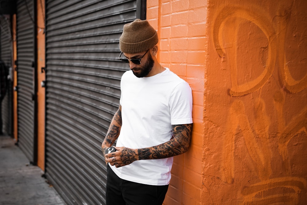 man in white crew neck t-shirt and black pants standing beside black wall