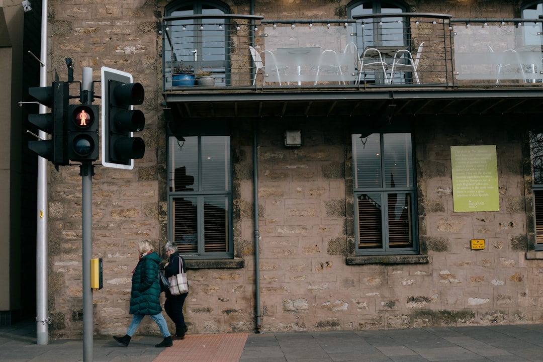 man in blue jacket and blue denim jeans standing in front of brown brick building