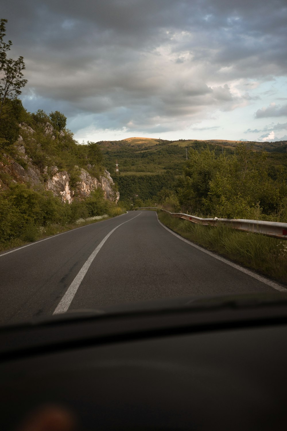 gray concrete road between green trees under white clouds during daytime