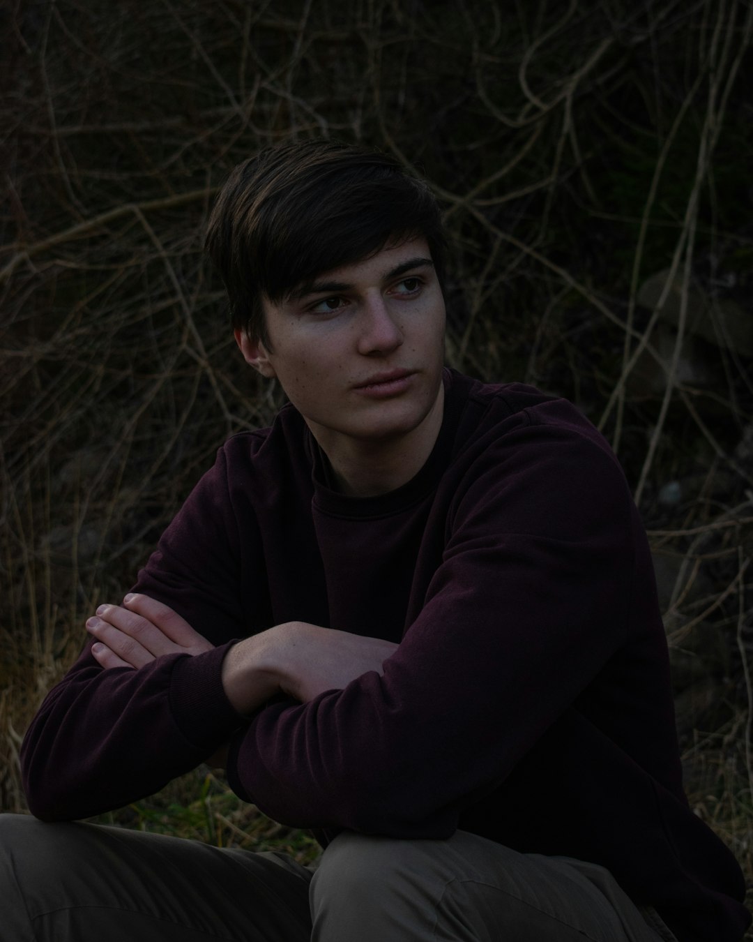 man in purple long sleeve shirt sitting on green grass field