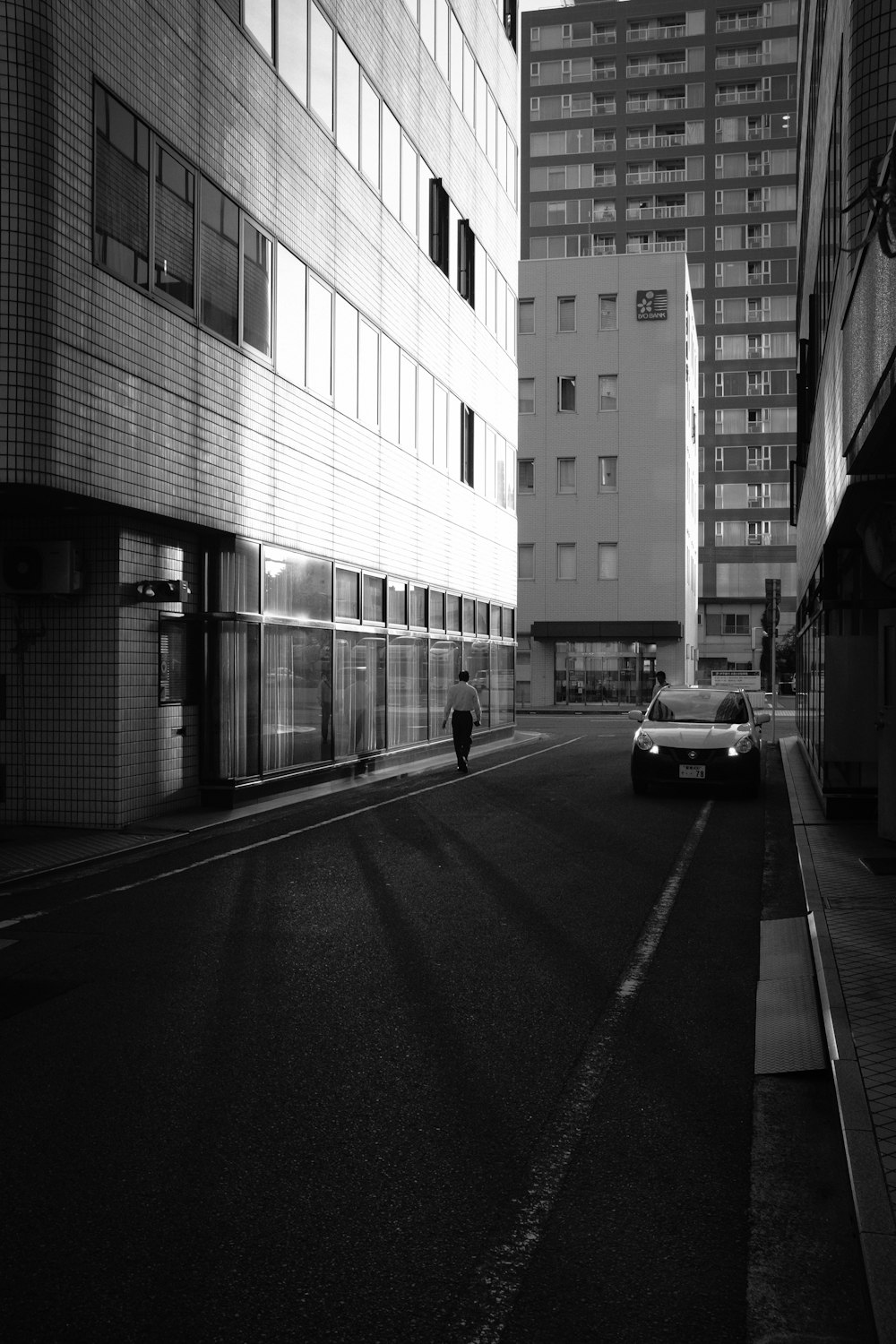 grayscale photo of car on road near building