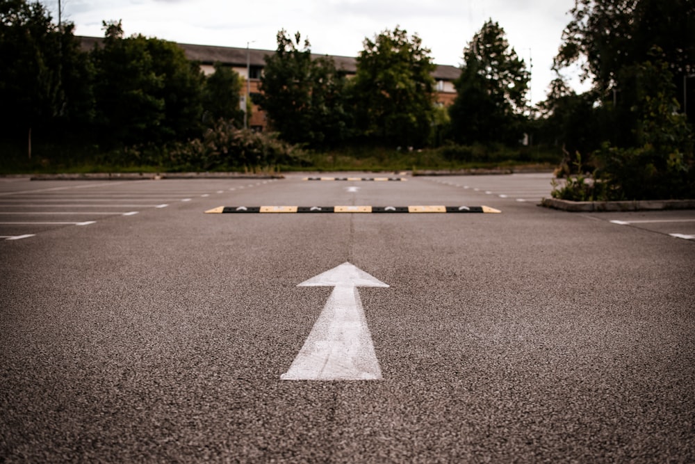 white arrow sign on gray asphalt road