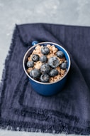 brown and black round fruits in blue ceramic bowl