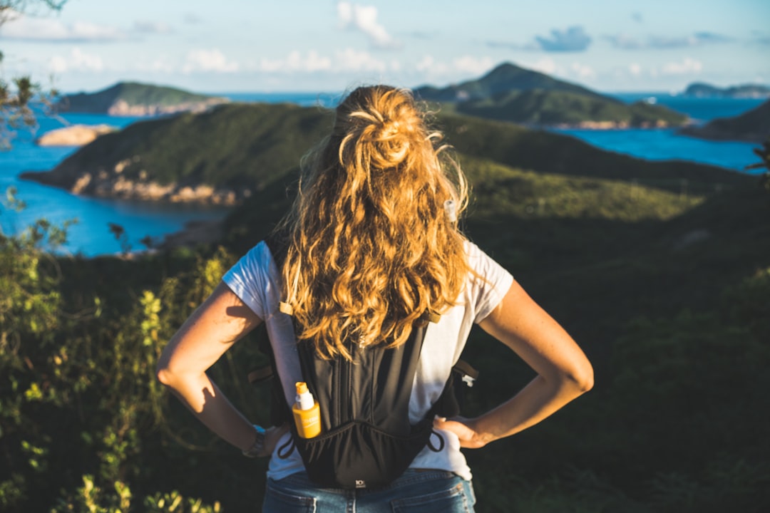 woman in white t-shirt and blue denim daisy dukes holding black and yellow labeled bottle