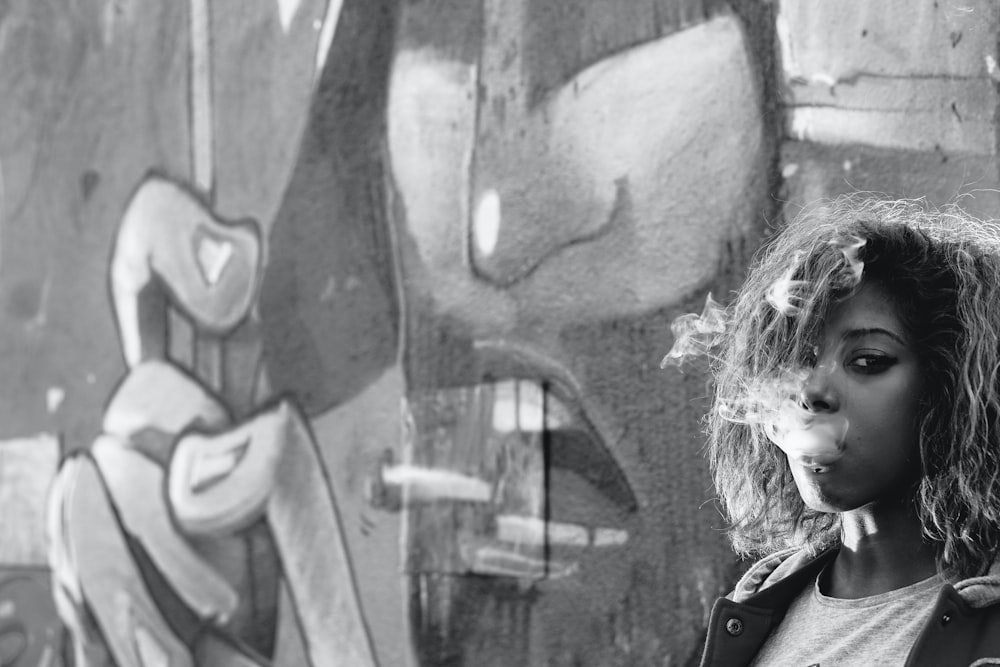 woman in black jacket standing beside wall with graffiti