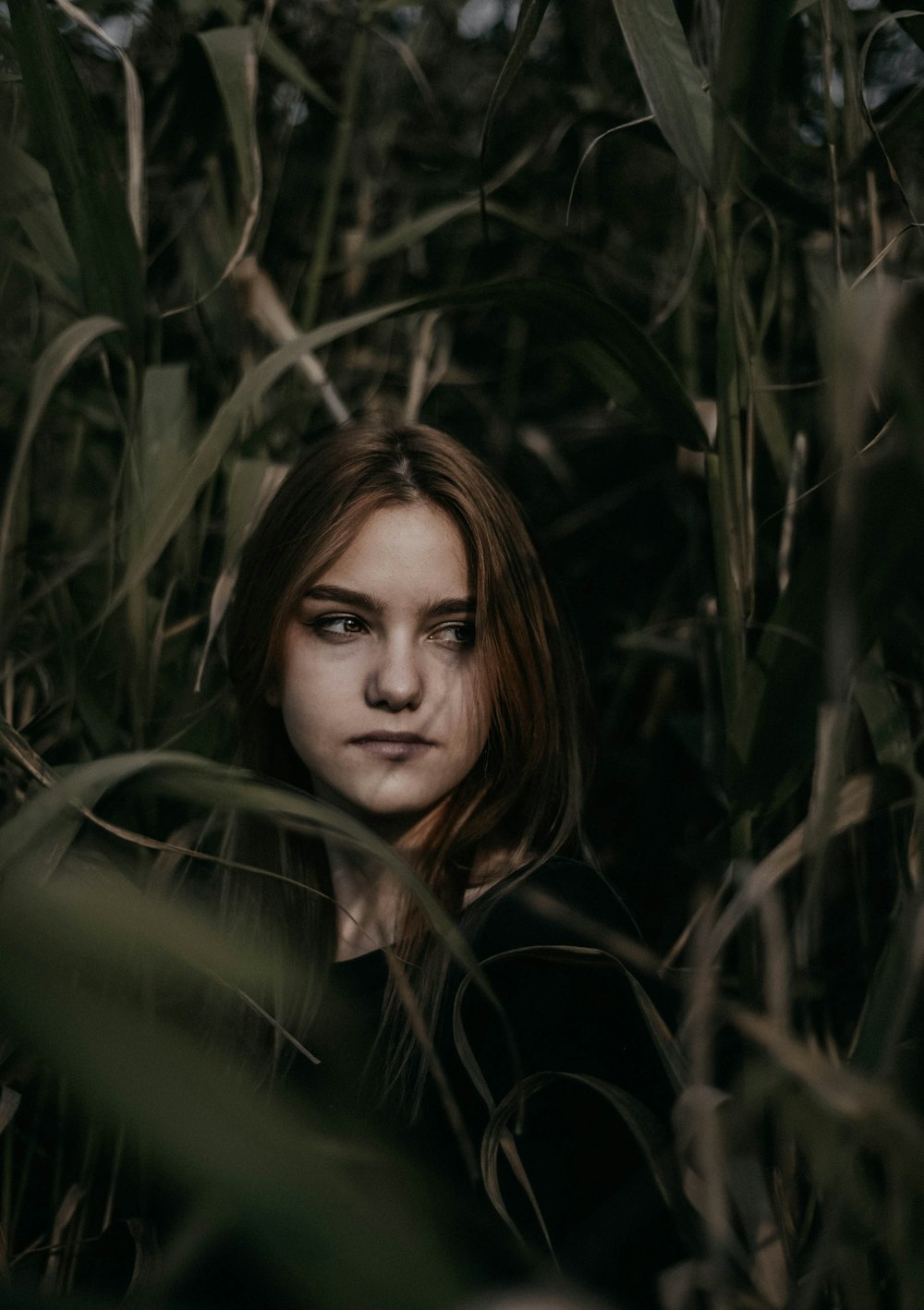 woman in black shirt surrounded by green plants