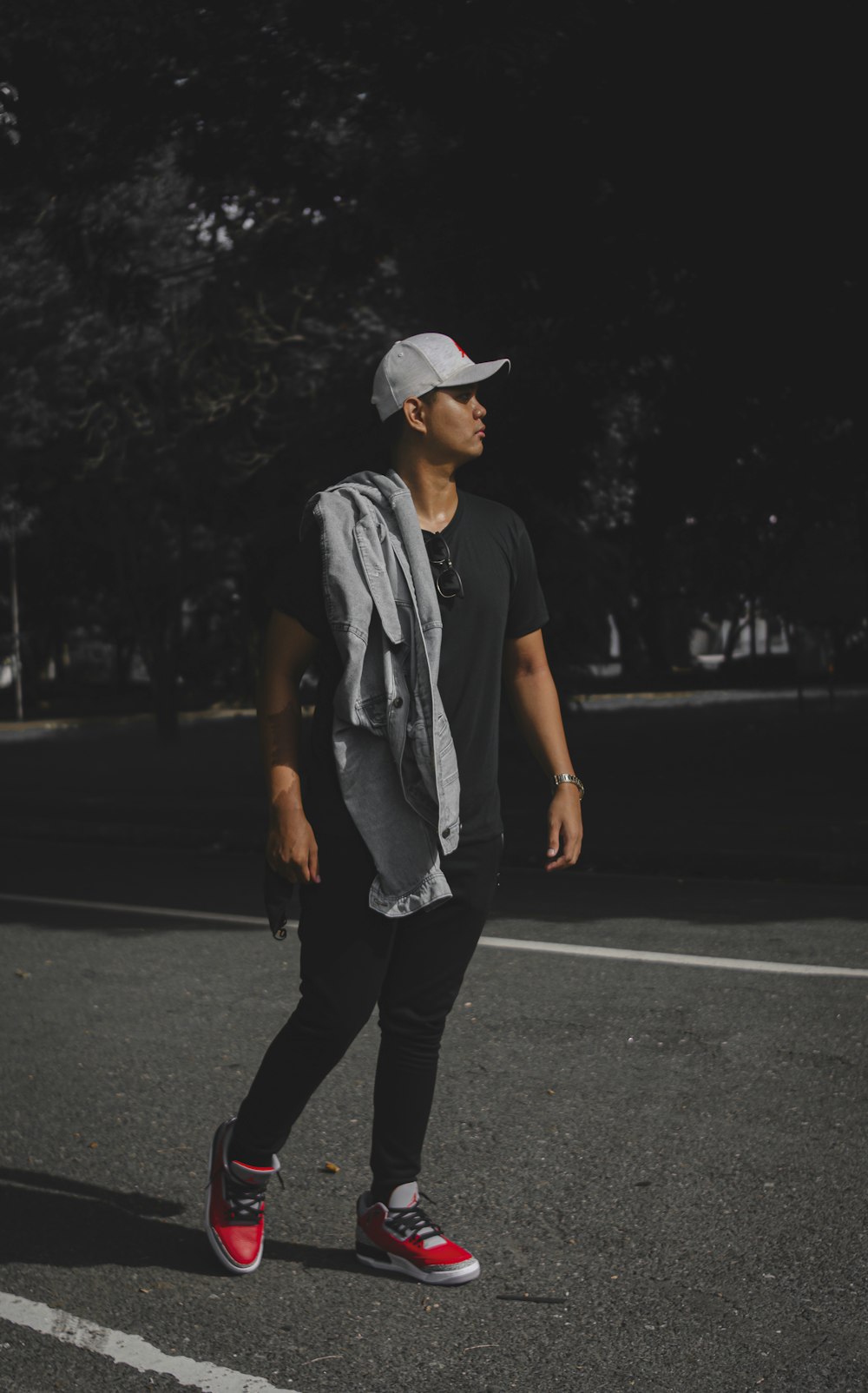 man in gray crew neck t-shirt and black pants wearing white cap standing on road