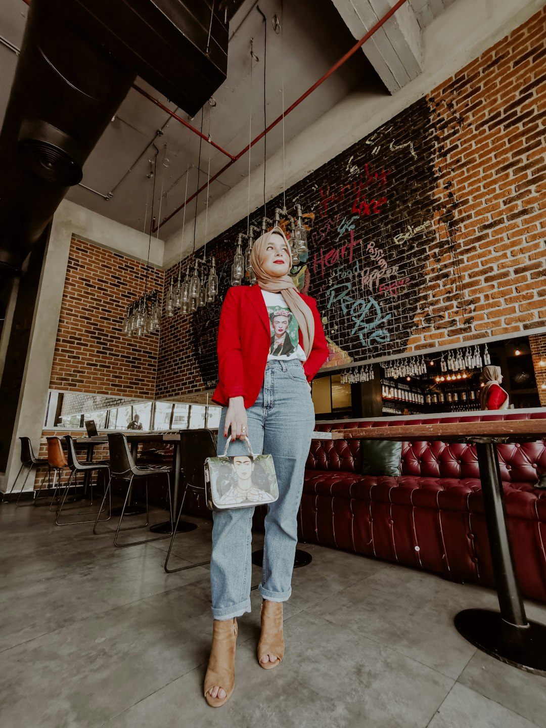 woman in red long sleeve shirt and blue denim jeans standing near red metal railings