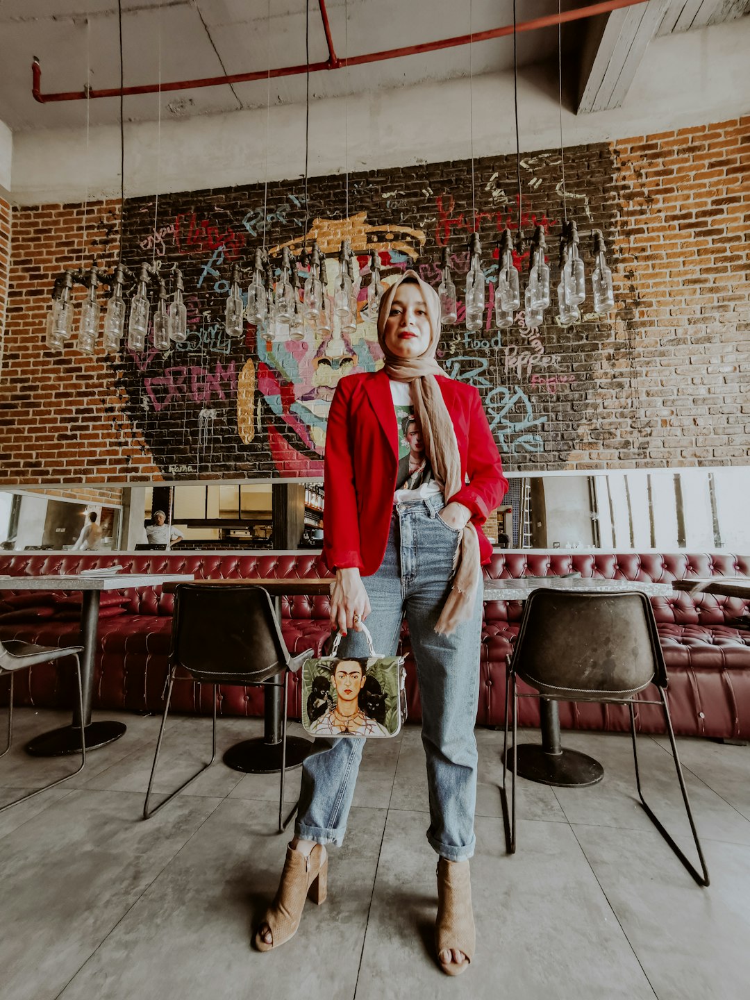 woman in red long sleeve shirt and blue denim jeans standing near red chairs