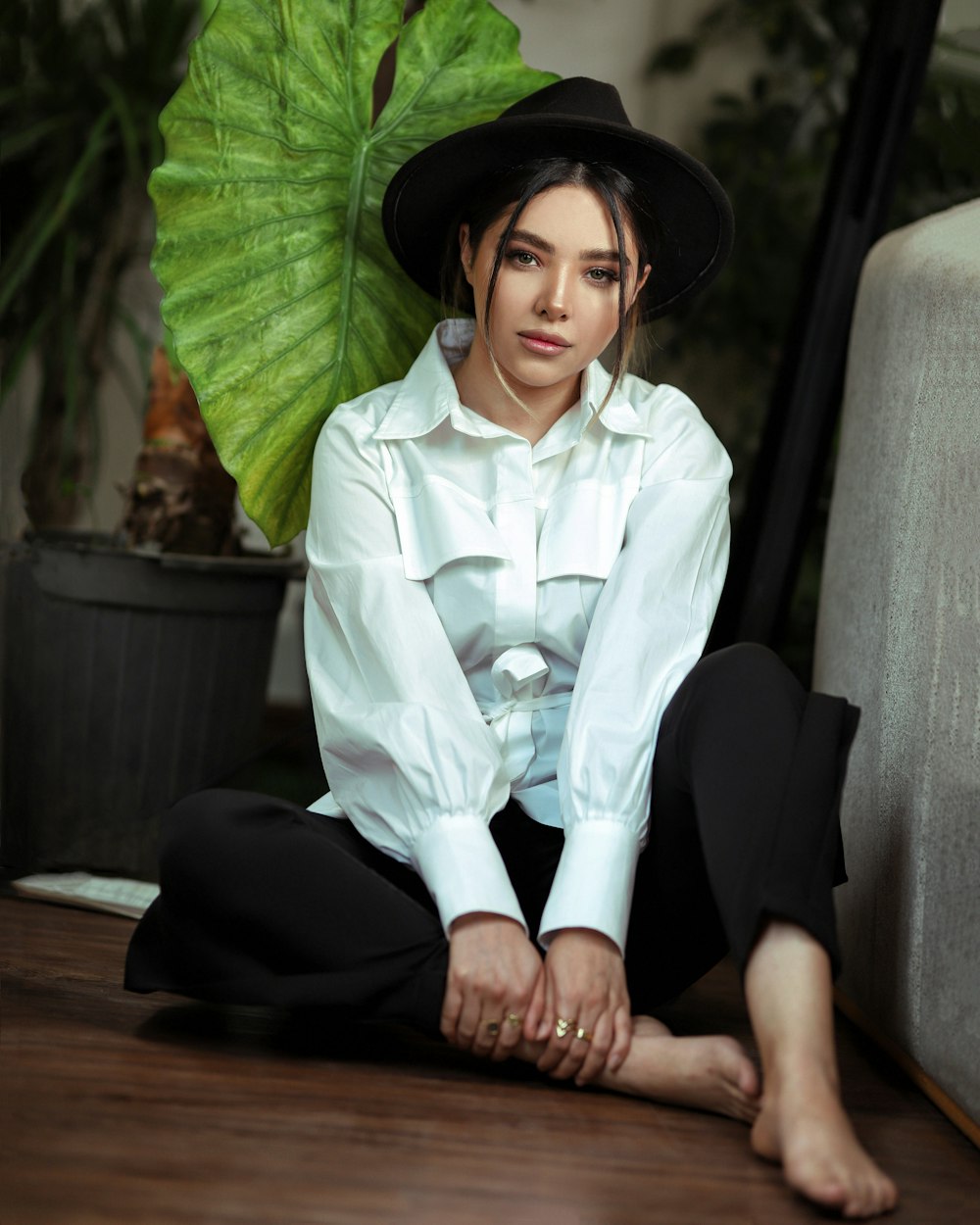 woman in white button up shirt and black pants sitting on gray sofa