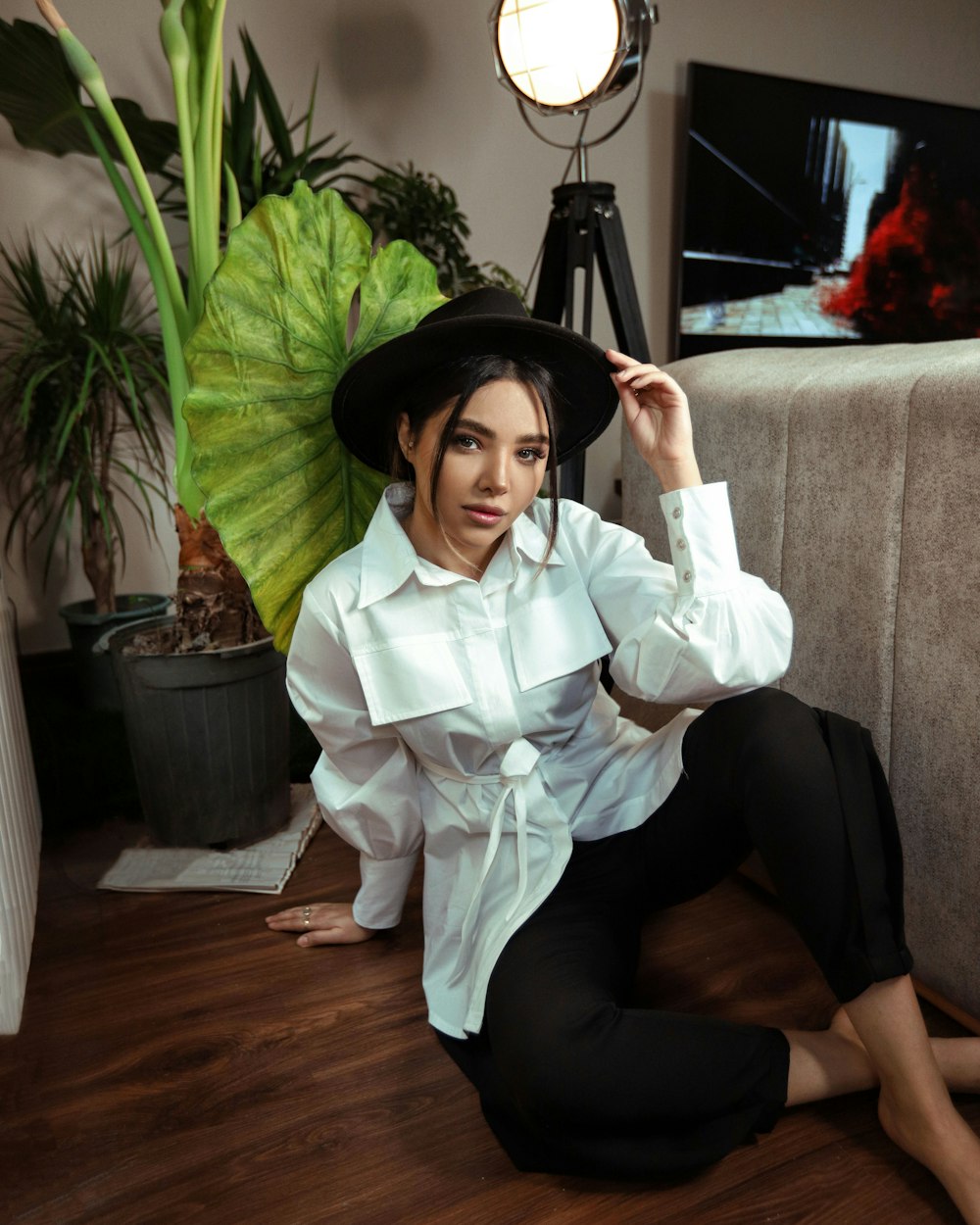 woman in white dress shirt and black pants sitting on gray couch