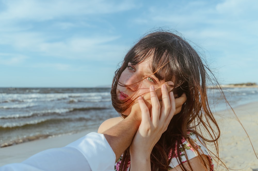 woman in white shirt covering her face with her hands