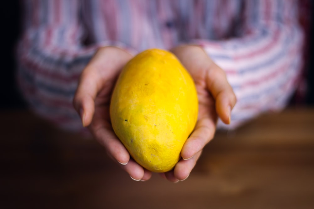 person holding yellow lemon fruit