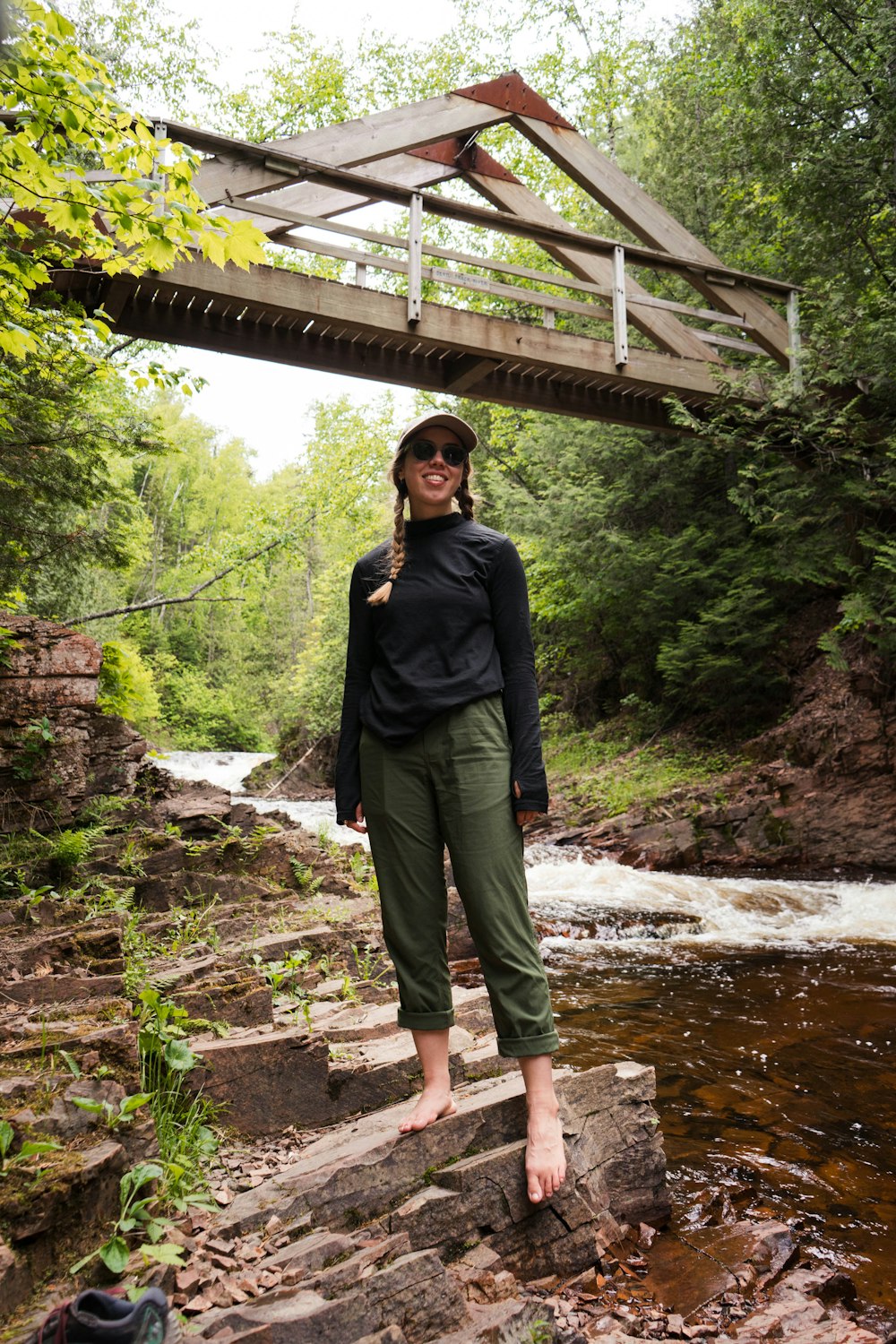 woman in black jacket standing on brown wooden bridge