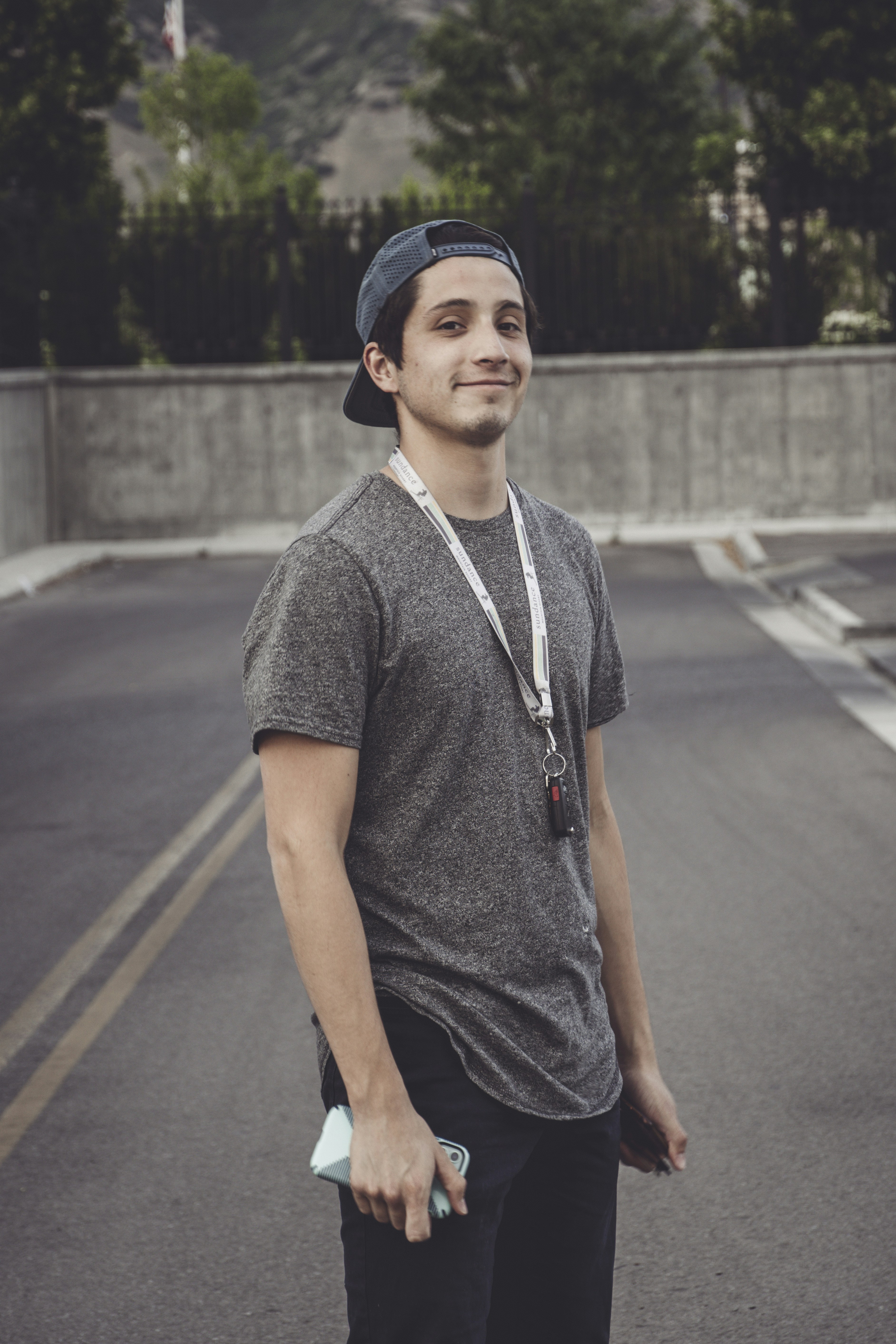 man in gray polo shirt and black cap standing on road during daytime