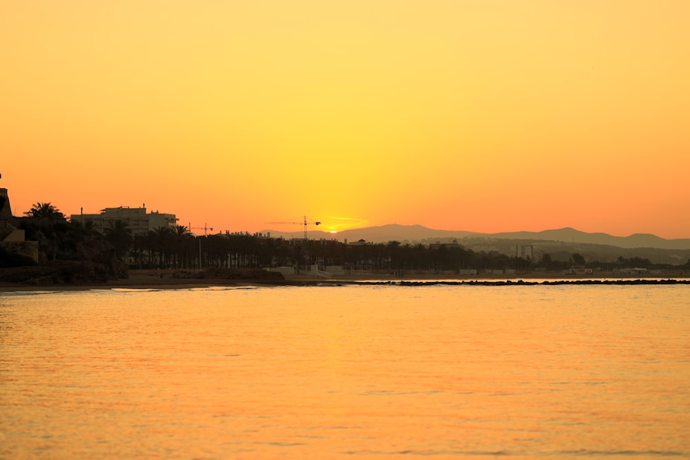 silhouette of building near body of water during sunset