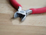 Set of precision pliers and cutters on a wooden work surface.