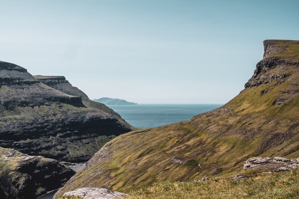 green grass covered mountain near sea during daytime