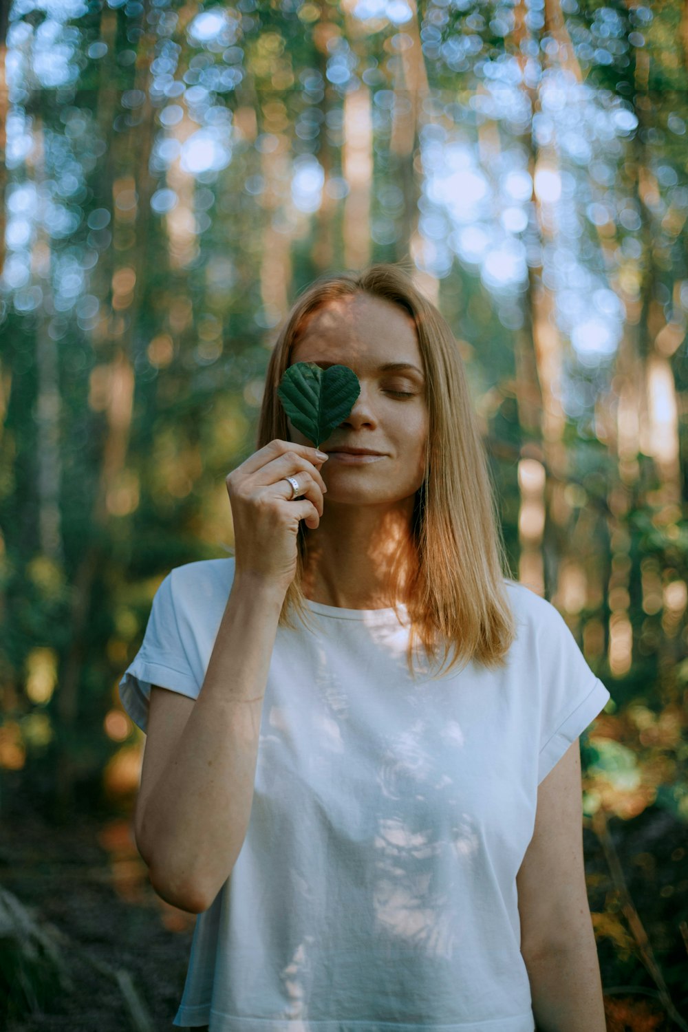 woman in white crew neck t-shirt holding her face