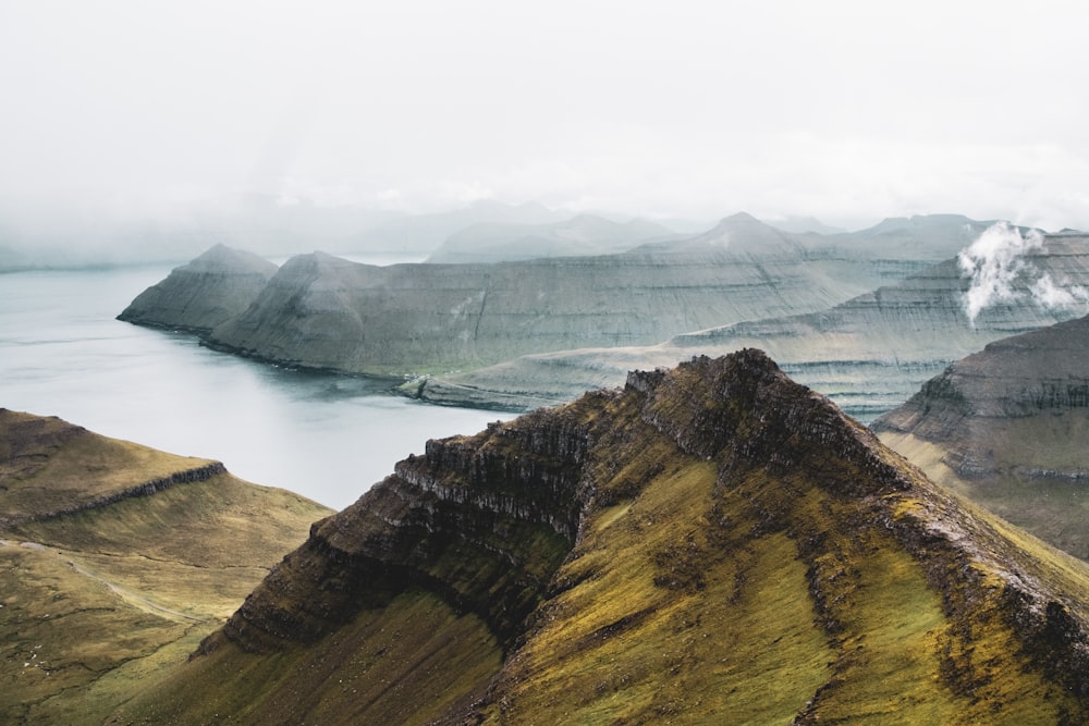 brown and green mountain beside body of water during daytime