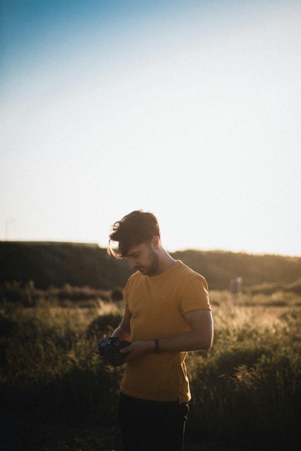 Hombre en camiseta marrón de cuello redondo de pie en el campo de hierba verde durante el día