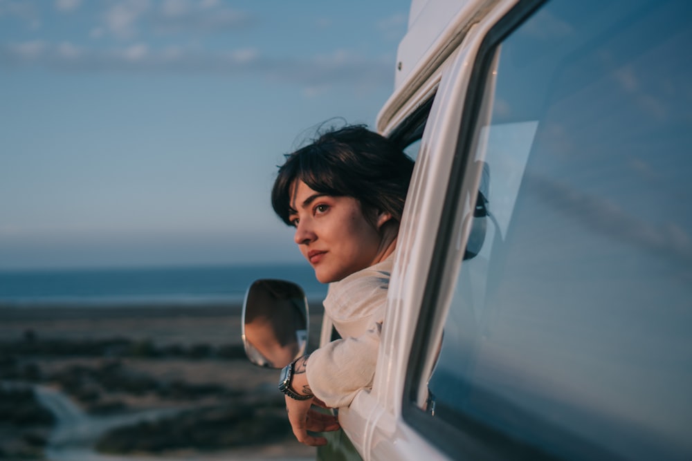 woman in white long sleeve shirt standing beside white car during daytime