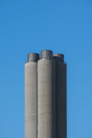 A large cement silo with the Real Mitra logo under a clear blue sky.