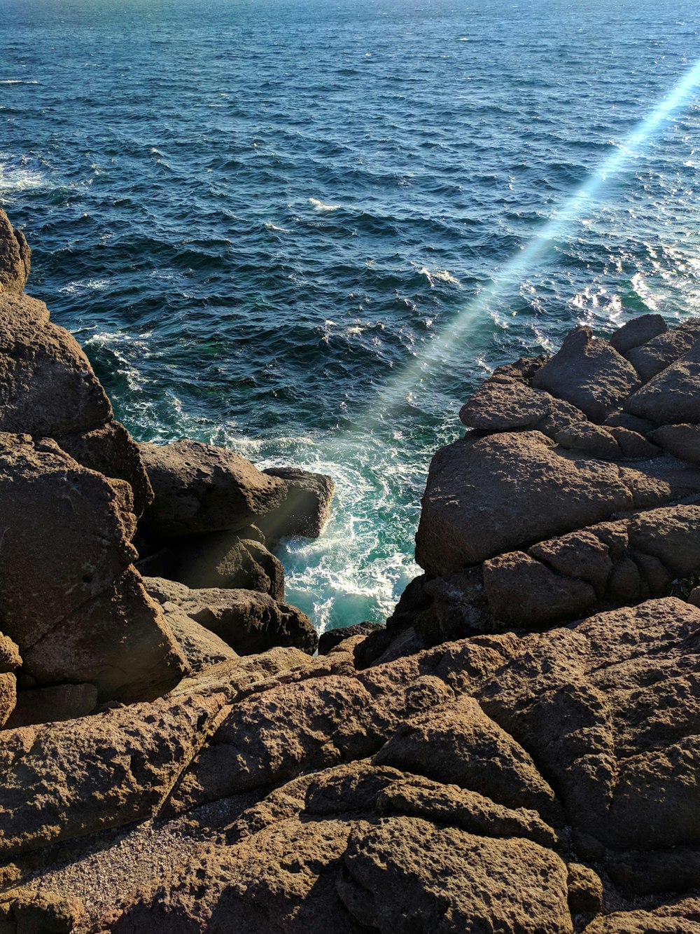 black rocks on body of water during daytime