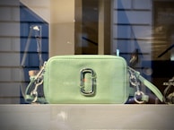 Minimalist gray crossbody bag from raphaauren displayed on a soft neutral fabric.