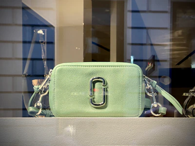 A colorful Omoluxe crossbody bag displayed on a minimalist wooden table.