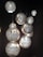 Several intricately designed, spherical pendant lights hang against a dark background. The lights feature detailed patterns with a mix of floral and geometric motifs, casting a warm, diffused glow.