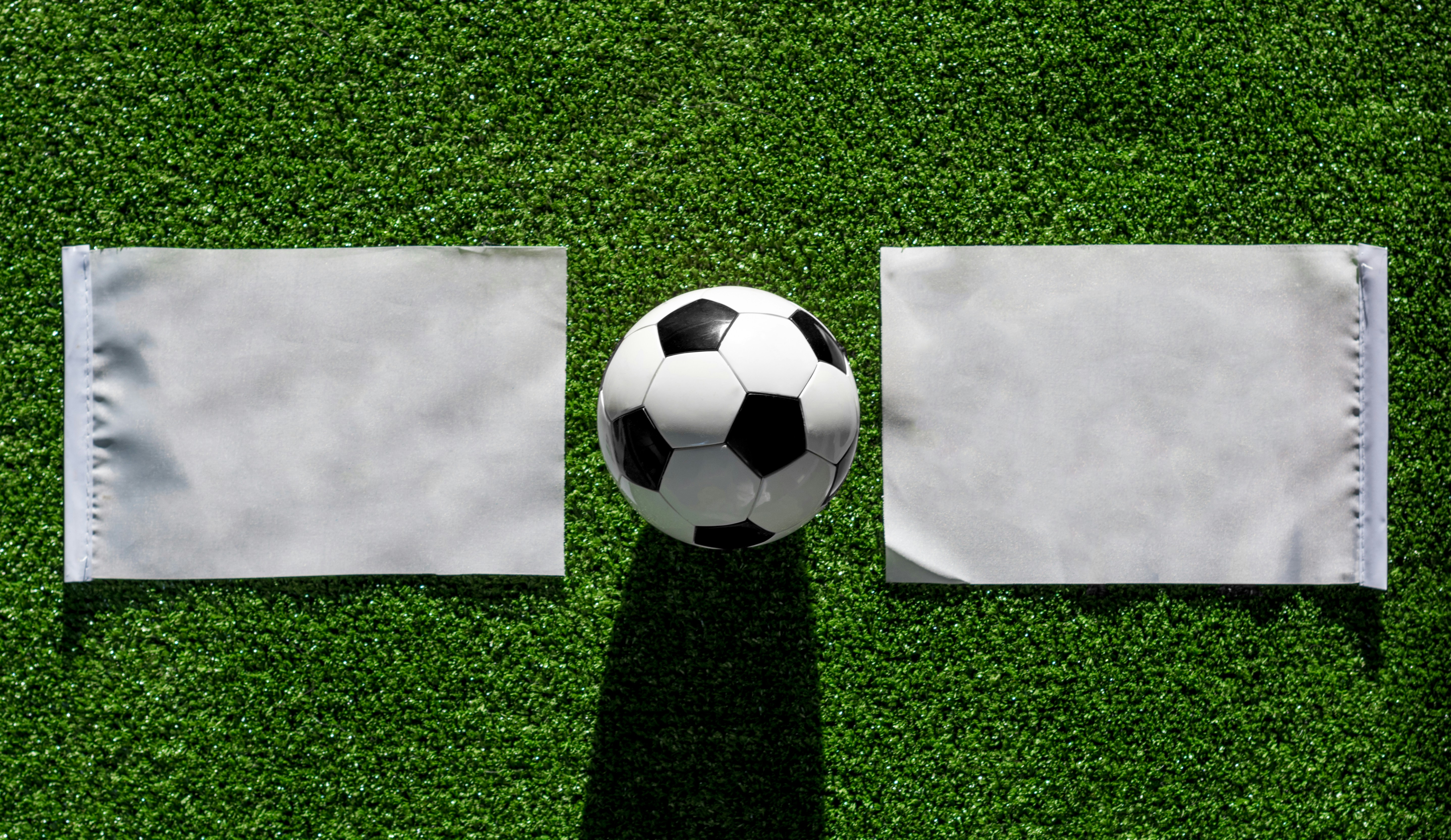 white soccer ball on green grass semi-abstract teams background