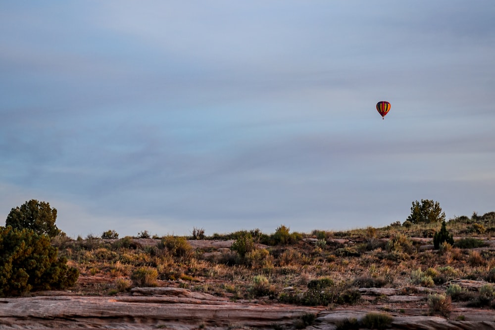 hot air balloon flying over green grass field during daytime