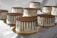 A collection of chocolate-dripped cakes arranged on gold-colored bases. Each cake is decorated with smooth white icing and topped with a glossy chocolate ganache that drips down the sides.