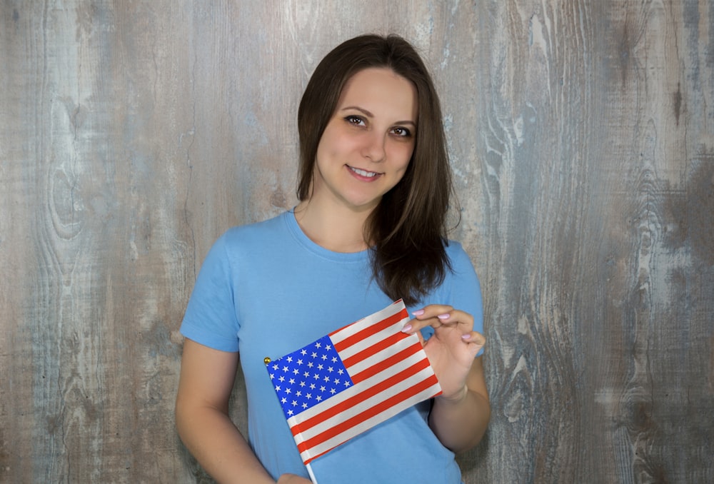 girl in blue crew neck t-shirt holding us a flag