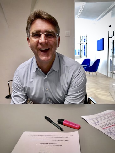 Smiling person reviewing a printed health protocol with rounded corners on a wooden desk.