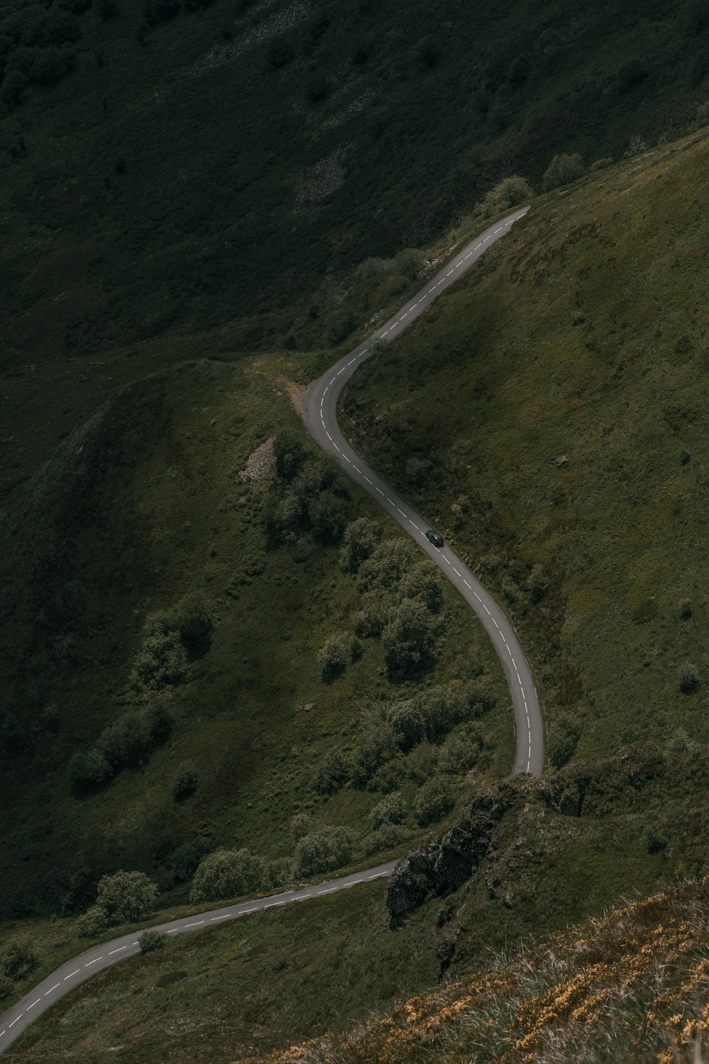 aerial view of road in the middle of green mountains